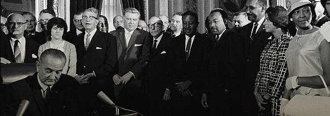 President Lyndon B. Johnson signs the Voting Rights Act as Martin Luther King Jr. and other civil rights leaders look on. LBJ Library Photo by Yoichi Okamoto