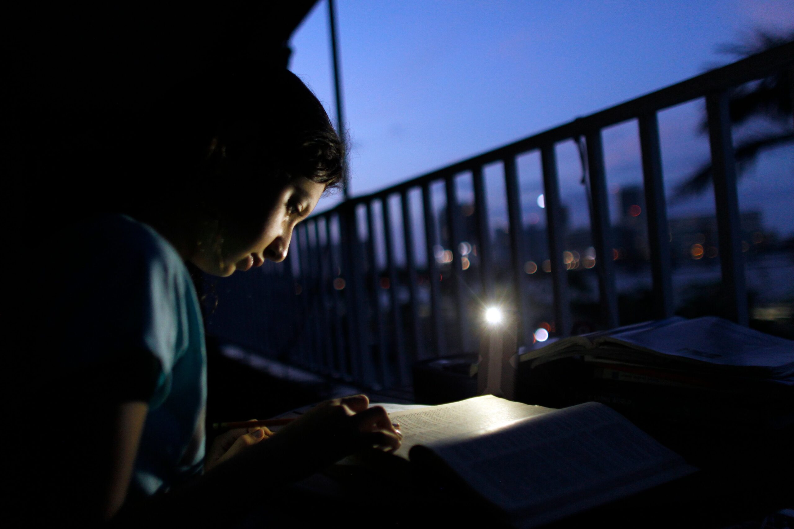 Alana Rivera, age 10, does her homework on her apartment balcony with the light of a cell phone, November 6, 2017. Her school reopened without electricity 46 days after Hurricane Maria hit Puerto Rico. (Photo: Ricardo Arduengo/AFP/Getty Images)