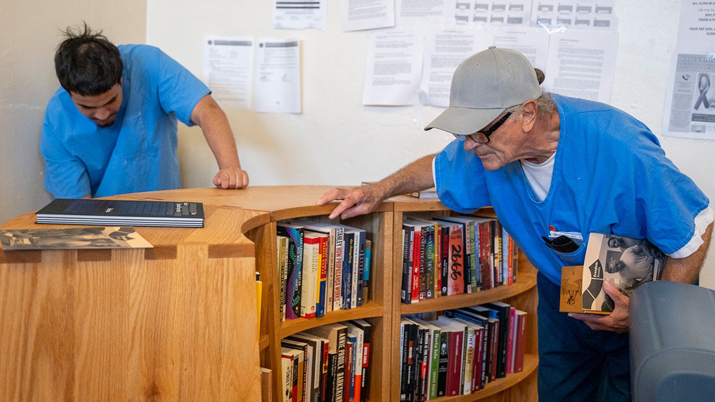 Two men browsing bookshelves at a Freedom Library in a California prison