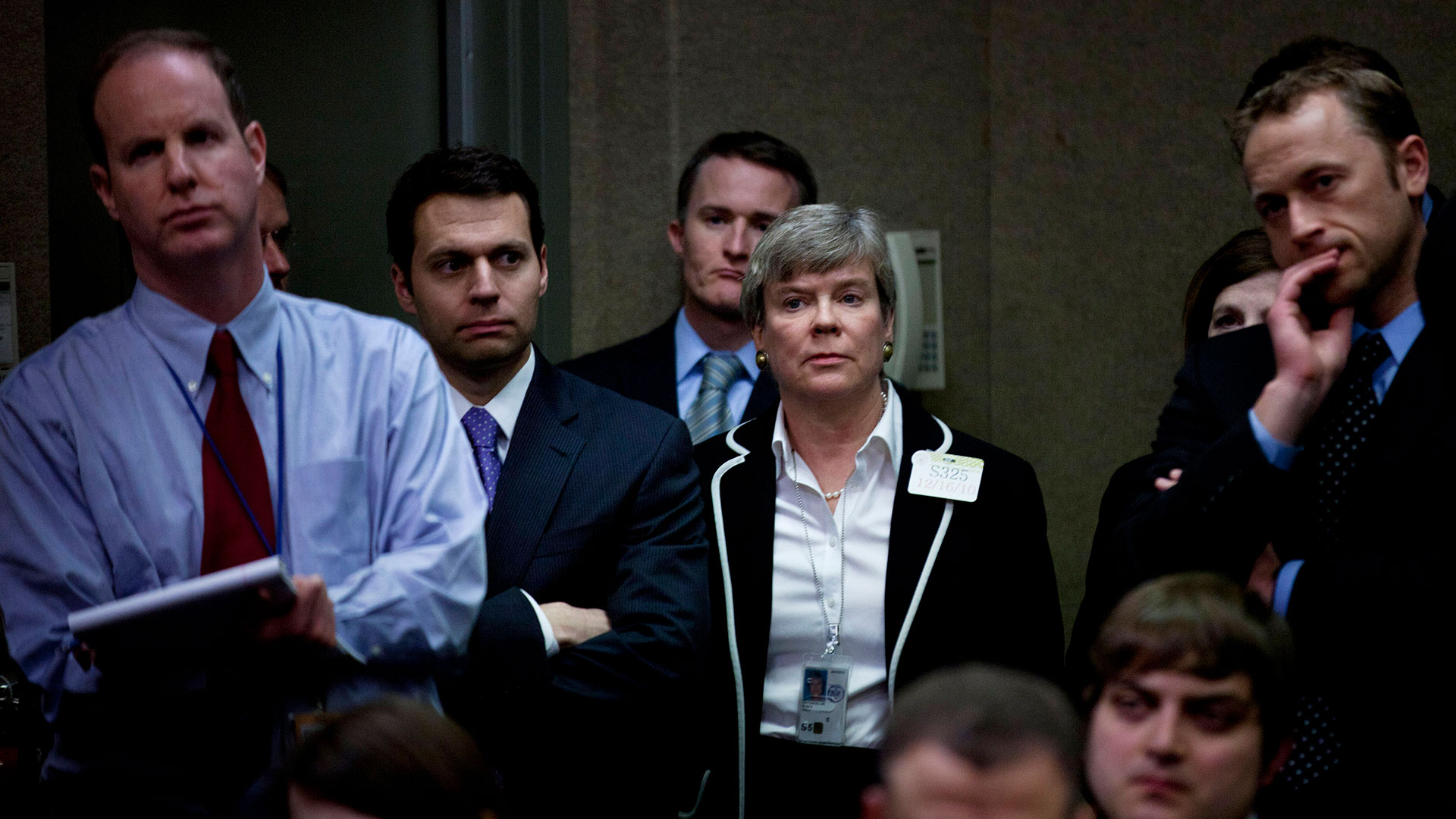 A woman standing among men in suits